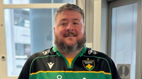 Simon Stacey wearing a Northampton Saints team shirt