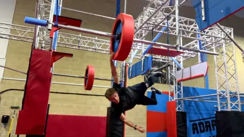 Tommy Matthews hanging off an obstacle