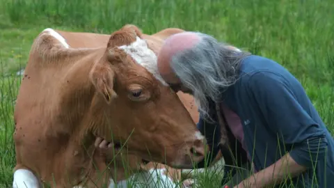 Cow and man sitting together