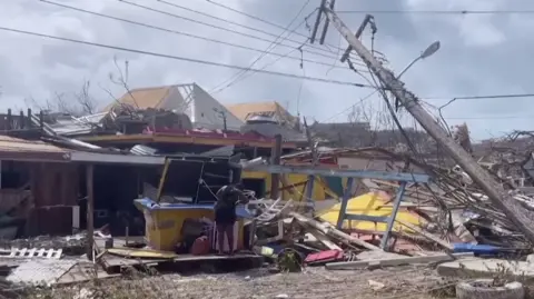 Person looking through damaged property in the aftermath of Hurricane Beryl after it passed Union Island