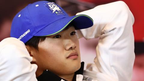 Yuki Tsunoda sits with his hands behind his head during a press conference