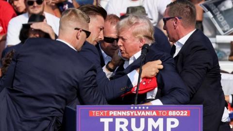 Donald Trump surrounded by staff