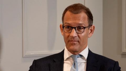 Daniel Kretinsky wearing black rimmed glasses, a suit and pale blue tie