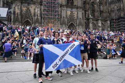 Scotland fans holding saltire outside Cologne cathedral