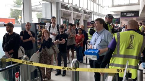 Passengers waiting at no entry barrier