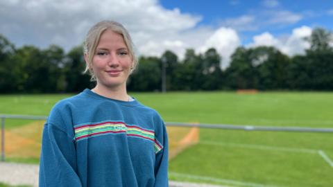 Shrewton United physio Issy Anderson standing in front of the club football pitch