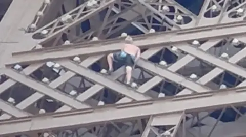 Man climbing the Eiffel Tower in Paris