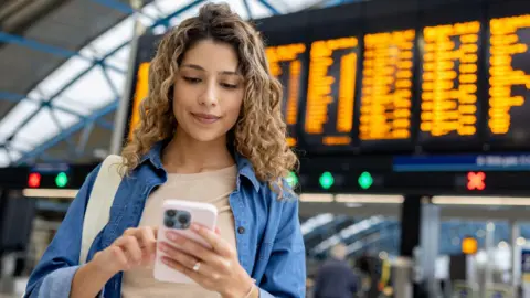 Woman buying ticket on phone at train station