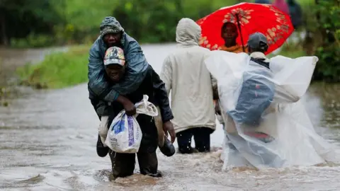 Reuters Residents wade through flood waters after a river burst its banks in heavy rainfall in Kitengela, near Nairobi, Kenya.