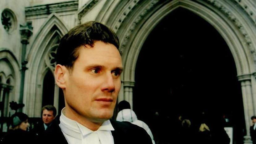 Sir Keir Starmer, dressed formally in his court silk gown, stands outside the Royal Courts of Justice in central London in 2006