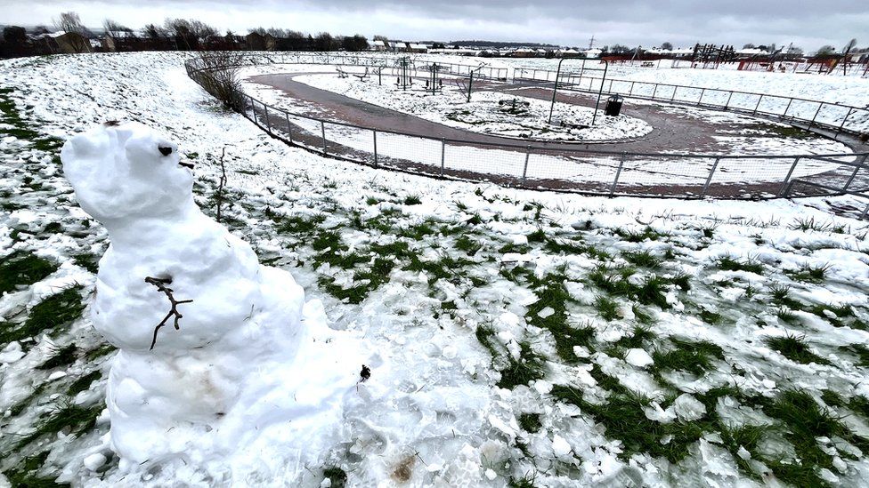 A snowman surrounded by melting snow in Elm Park in Filton