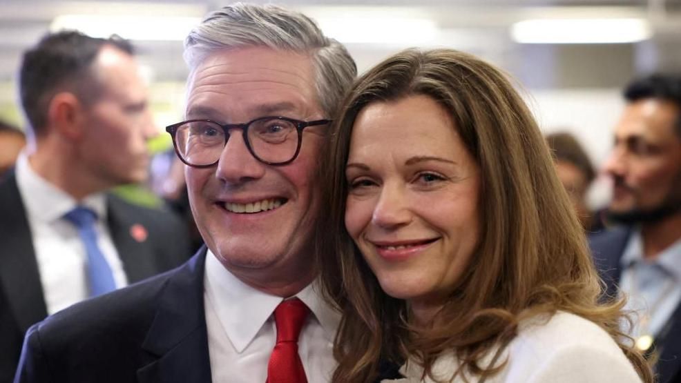 Sir Keir Starmer and Lady Starmer stand beside each other smiling