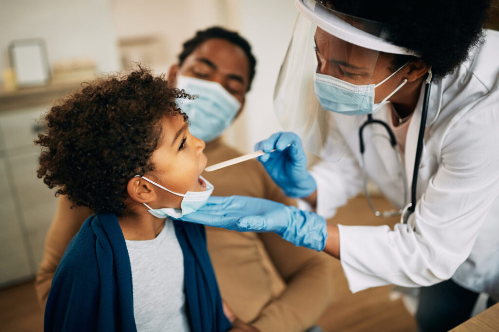 Family doctor examining throat of a young patient