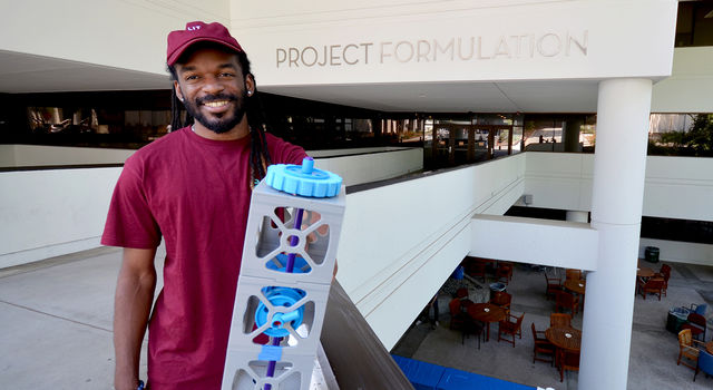 JPL intern Joshua Gaston holds a 3-D printed model of a CubeSat