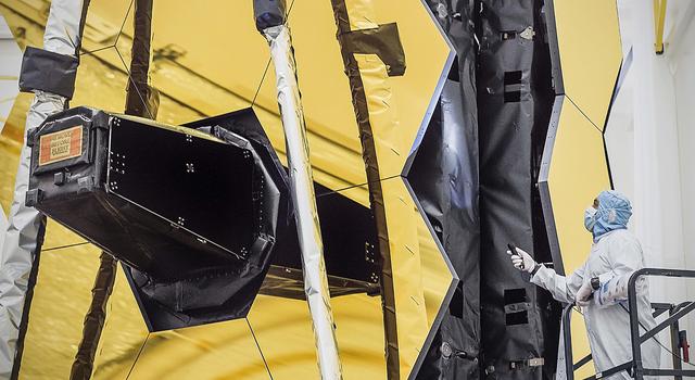 In the cleanroom at Northrop Grumman, a technician inspects the bellows between the hexagonal sections that make up the large honeycomb-shaped mirror on the Webb telescope.