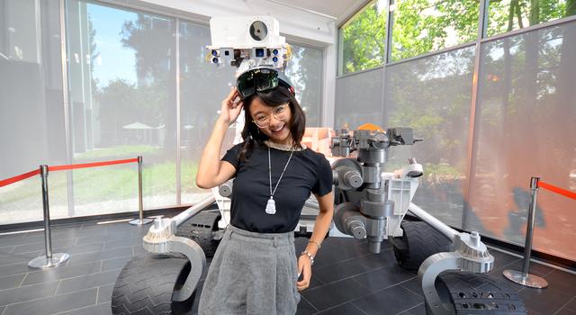 Michelle Vo poses for a photo in front of a full-size model of the Curiosity Mars rover at JPL.