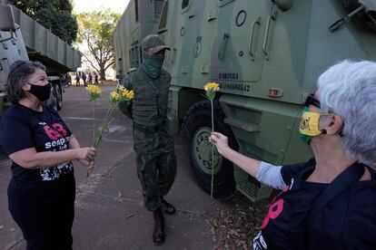 Mulheres entregam flores a militar em dia de desfile de tanques em Brasília, em 10 de agosto.