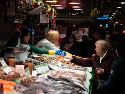 Una comerciante cobra a una señora, en el Mercado de la Boquería, en Barcelona.