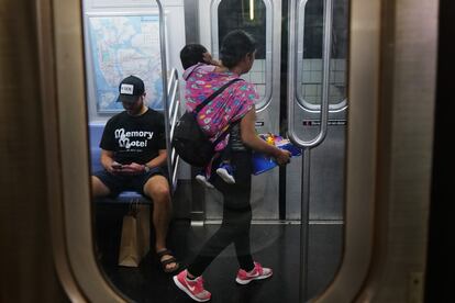 Una joven vende dulces con su hijo a cuestas dentro de un vagón del metro de Nueva York. 