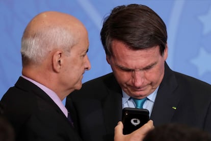 Bolsonaro olha telefone segurado pelo ministro da Secretaria-Geral da Presidência, Luiz Eduardo Ramos, em setembro de 2020.