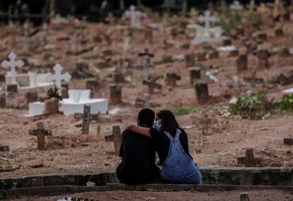 Familiares de vítima de covid-19, sepultada no Rio de Janeiro, se apoiam em cemitério em imagem de abril de 2021