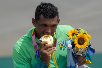 Isaquias Queiroz morde sua medalha de ouro na canoagem.