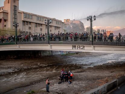 Un joven es atendido por personal de rescate en el lecho del río Mapocho, luego que un carabinero antimotines lo lanzara desde el puente Pío Nono, en octubre de 2020.