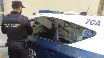 Un agente de la Policía Nacional de espaldas, junto a un coche patrulla, en una imagen de archivo.