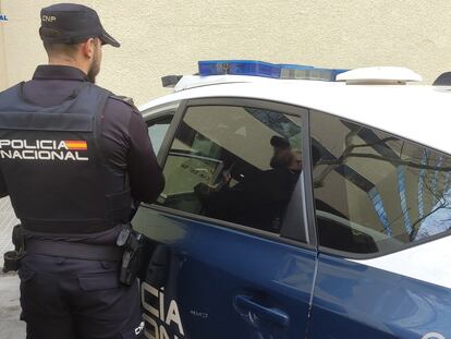 Un agente de la Policía Nacional, junto a un coche patrulla en agosto de 2023.