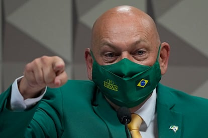 Department store magnate Luciano Hang, wearing Brazil's national colors, testifies before a Senate hearing investigating Jair Bolsonaro administration’s handling of the COVID-19 pandemic, in Brasilia, Brazil, Wednesday, Sept. 29, 2021. Hang's mother died at one of the health care company's hospitals under inquiry. (AP Photo/Eraldo Peres)