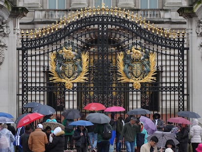 Los turistas se refugian de la lluvia bajo paraguas a las puertas del Palacio de Buckingham, en el centro de Londres.