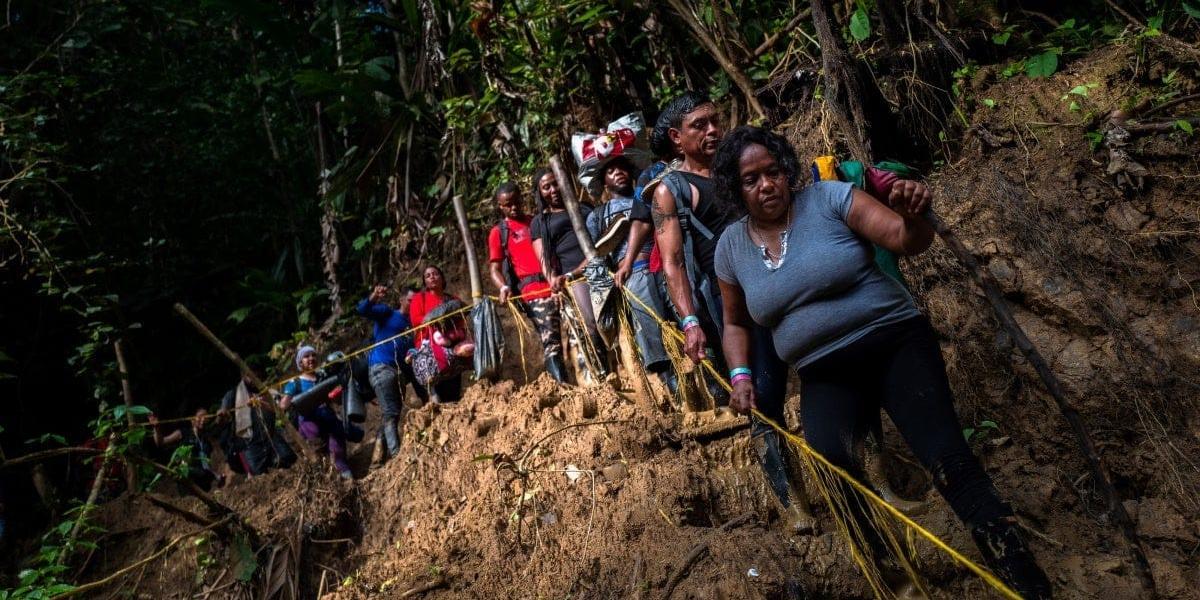 Migrantes descienden por un sendero pantanoso en el Tapón del Darién.