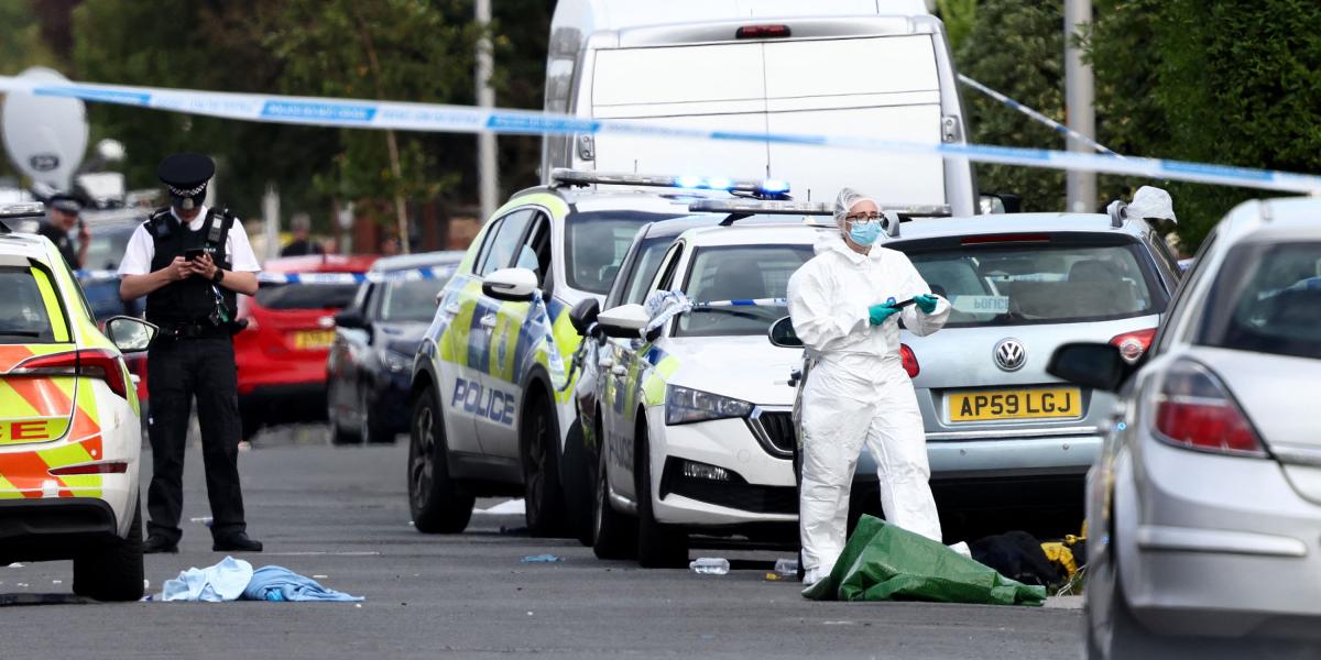 Agentes de policía y personal forense se encuentran detrás de un cordón en Hart Street en Southport, noroeste de Inglaterra, el 29 de julio de 2024, tras un ataque con cuchillo que causó la muerte de dos menores.