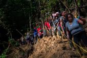 Migrantes descienden por un sendero pantanoso en el Tapón del Darién.