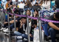 Pasajeros esperan para facturar en el Aeropuerto Internacional de Hong Kong, mientras algunas aerolíneas recurren a la facturación manual.