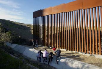 Migrantes hondureños tratando de cruzar el muro en la frontera sur estadounidense con Tijuana (México).