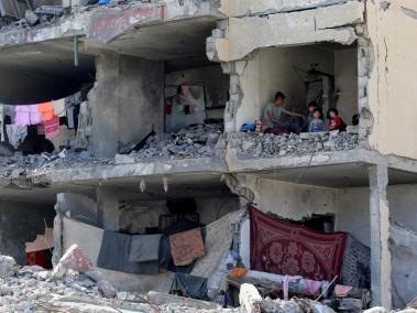 Un palestino y sus hijos sentados en una habitación destruida tras un ataque aéreo israelí contra un edificio residencial en Rafah.