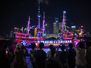 La gente mira un crucero y la luna llena en el paseo del Bund, a lo largo del río Huangpu, en Shanghai.