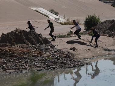 Migrantes venezolanos corren después de cruzar el Río Bravo, o Río Grande como se le llama en los EE. UU.