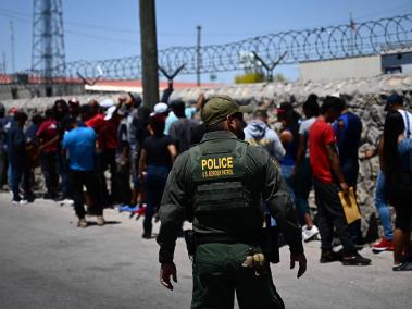 Un agente de la Patrulla Fronteriza camina a lo largo de una fila de migrantes.