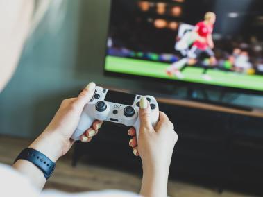 Girl playing a video game console. Game is football. Joystick in hands. Selective focus