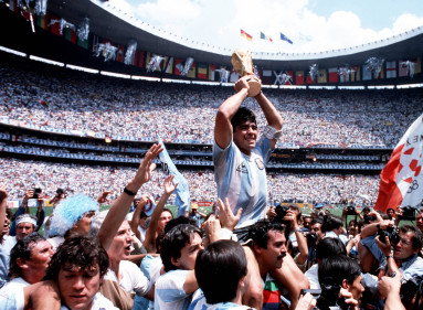 Un momento icónico de la carrera de Maradona: cargado a hombros tras la final de la Copa del Mundo en el Azteca en 1986. En medio de un tumulto de fanáticos, periodistas y fotógrafos, se puede ver cómo los espectadores y los hinchas tiran su camiseta y hacen todo lo posible por tocarlo; todo el mundo quiere un pedazo de Diego.