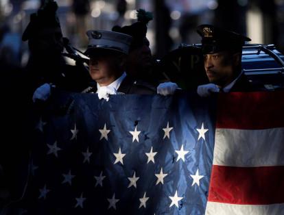 Al inicio de la ceremonia conmemorativa en el "9/11 Memorial", bomberos de Nueva York sostienen la bandera que una vez estuvo izada en el World Trade Center. Se alcanzan a ver hoyos en la tela de la bandera.