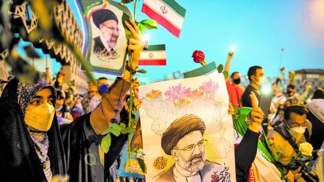 Partidarios de Ebrahim Raisí, presidente de Irán, sostienen fotos suyas mientras celebran su victoria en las elecciones presidenciales en la plaza Imam Hossein, en Teherán (Irán), el 19 de junio.