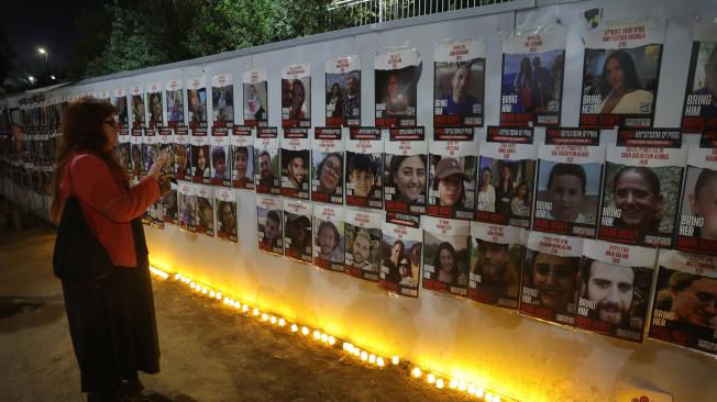 La gente enciende velas junto a fotografías de rehenes y víctimas israelíes mientras conmemoran un mes desde el ataque de Hamás contra Israel el 7 de octubre.