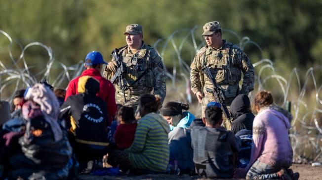 Tropas de la Guardia Nacional de Texas vigilan a algunos de los más de 1.000 inmigrantes que cruzaron el Río Grande desde México.