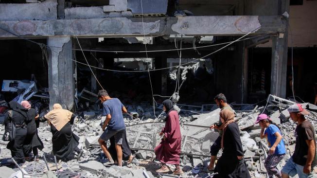 Un grupo de personas se abre paso entre los escombros de los edificios destruidos durante los bombardeos israelíes.