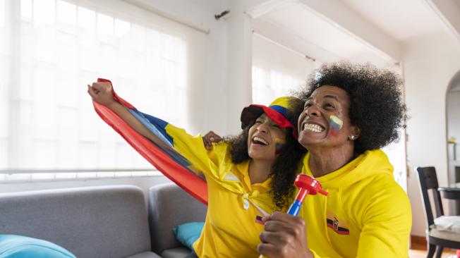 afro couple of friends with an average age of 25 years old fans of the Ecuadorian soccer team prepare at home for the match dressed in shirts of their team's selection and flag in the room