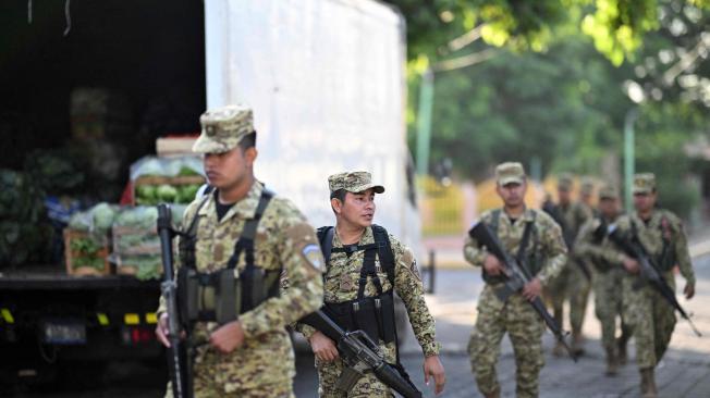 Soldados caminan junto a un punto mayorista de hortalizas promovido por el gobierno para beneficiar a los pequeños y medianos compradores en el municipio de Apopa, El Salvador, el 9 de julio de 2024.