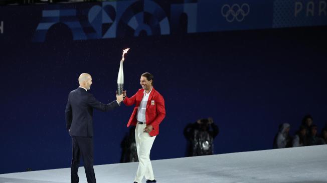 El tenista español Rafa Nadal (i) recoge la antorcha olímpica de manos del exfutbolista Zinedine Zidane en la Plaza del Trocadero durante la ceremonia de inauguración de los Juegos Olímpicos de París 2024, este viernes en la capital francesa.